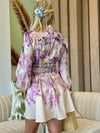 Model wearing romantic pink and lilac print dress with high collar.