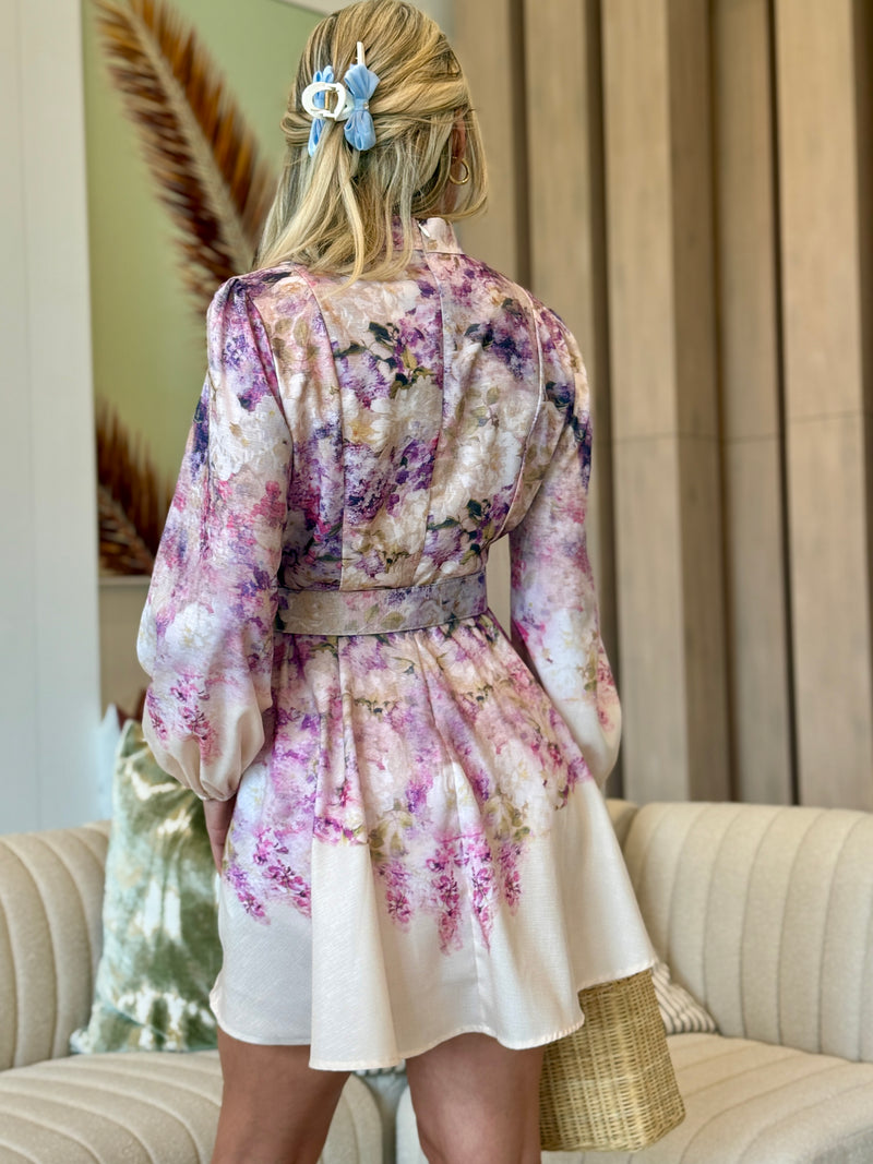 Model wearing romantic pink and lilac print dress with high collar.