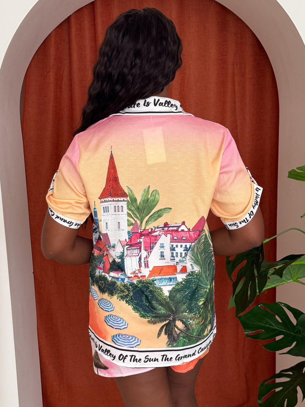Woman in peach scenic print short set with umbrellas and canyon views.