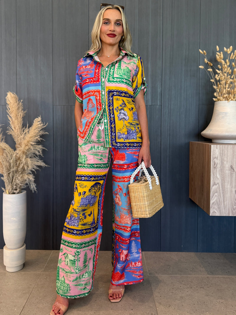 Woman in colorful patchwork resort set with toile landscape prints.