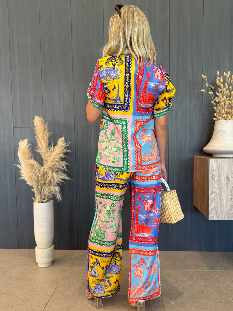 Model wearing multicolor two-piece set featuring vintage-style scenery.