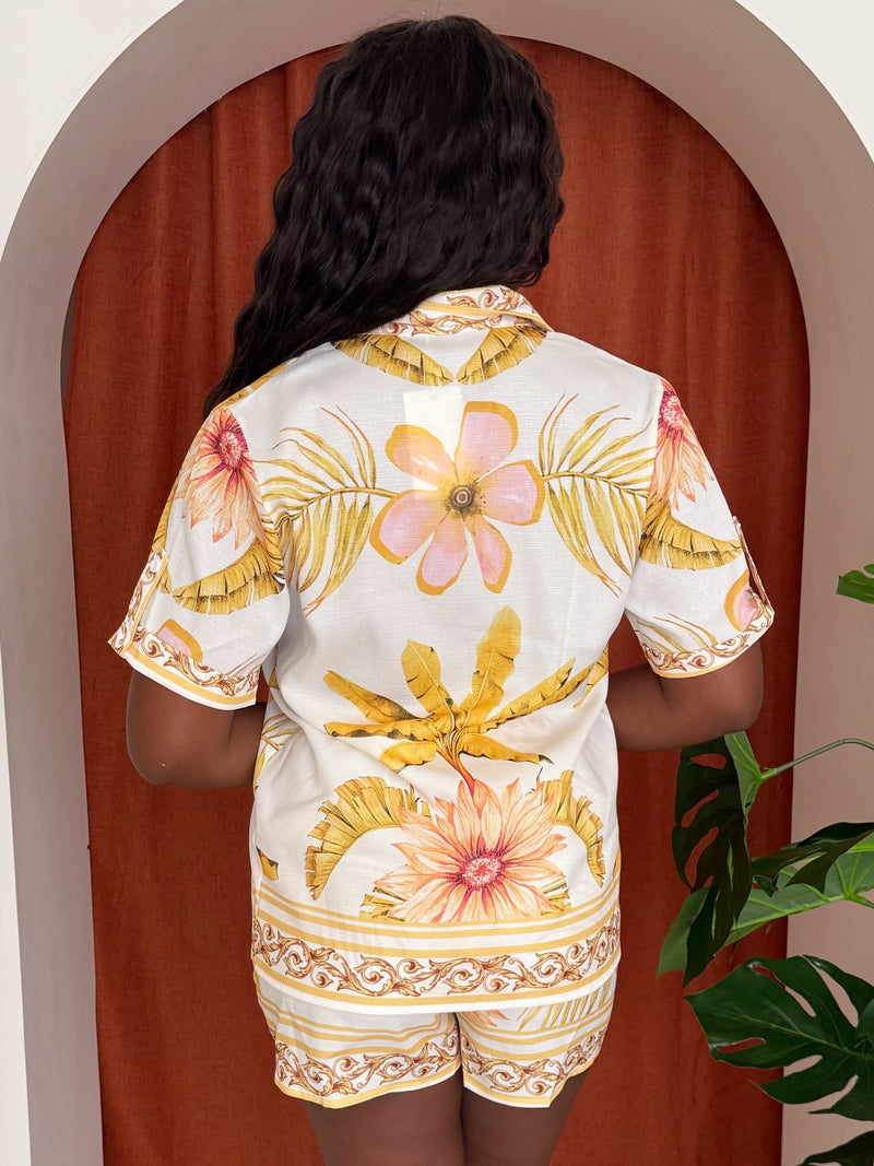 Model wearing floral two-piece set with yellow and coral tones.