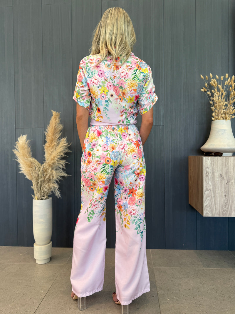 Model wearing silky pink two-piece set with colorful floral print.