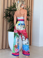 Model wearing bold postcard-inspired jumpsuit in bright pink and blue.