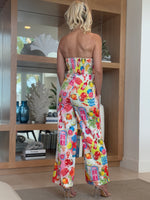 Model wearing wide-leg jumpsuit featuring citrus, signage, and grocery icons.