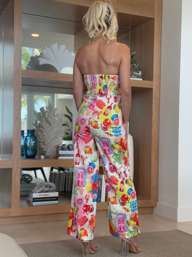 Model wearing wide-leg jumpsuit featuring citrus, signage, and grocery icons.