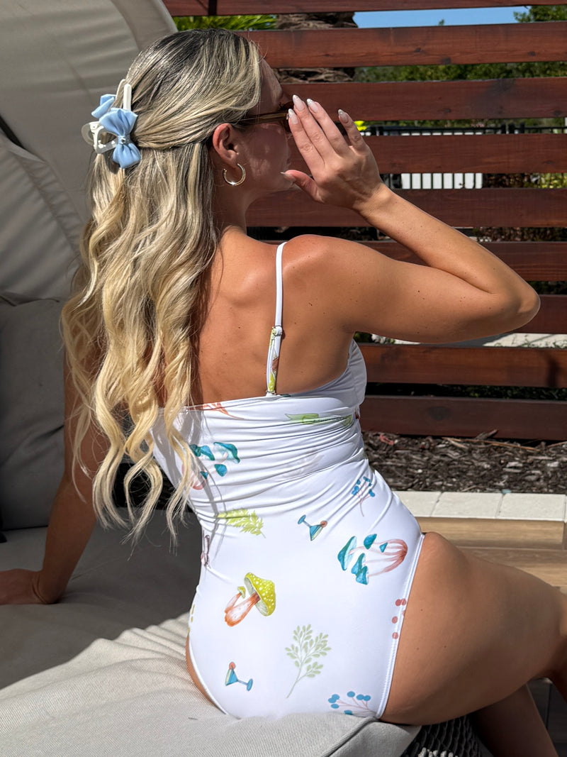 Model in white swimsuit with illustrated cocktails and mushrooms