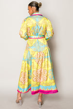Model wearing a colorful long-sleeve vacation dress with pink trim